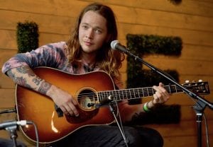 Billy Strings plays an acoustic guitar on stage