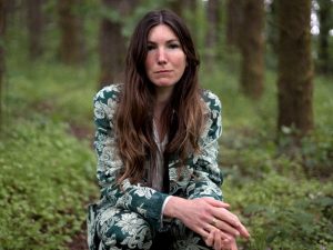 Anna Tivel in the woods in a green and white outfit